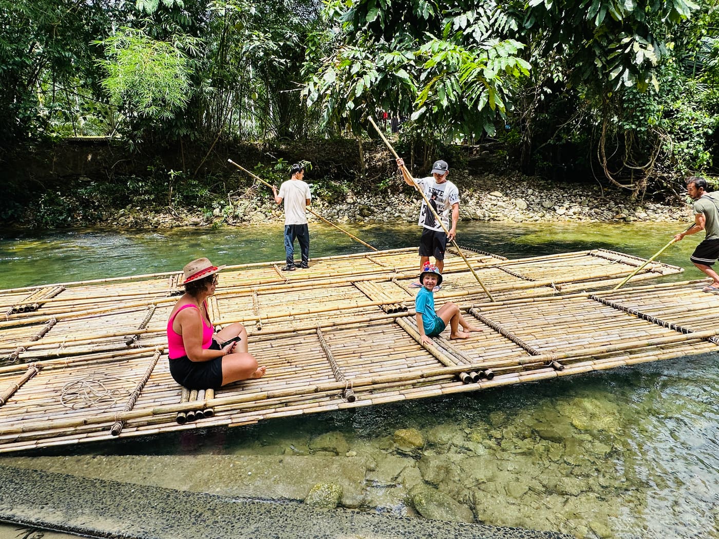 Family bamboo rafting on a clear river